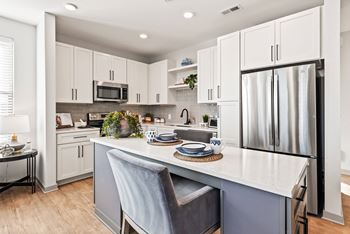 A kitchen with a white countertop and a grey chair.